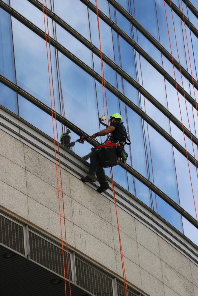 A window cleaner using ropes on a modern skyscraper in daylight.