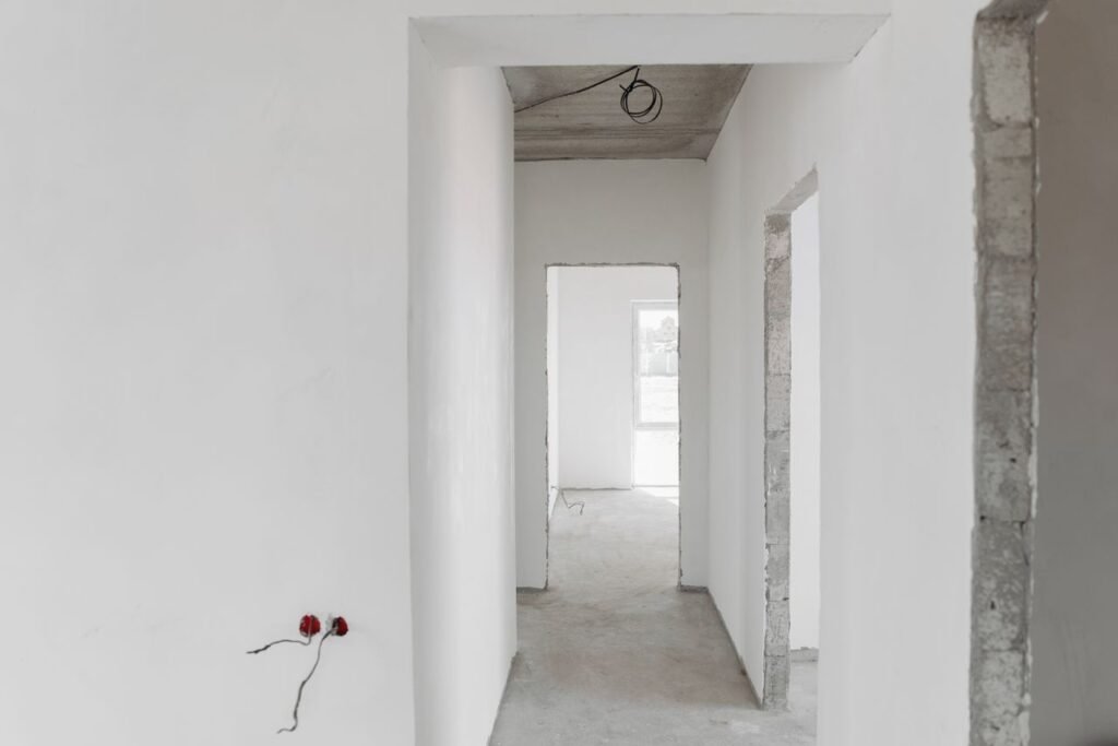 A minimalist view of an unfinished building interior with white walls and door frames.